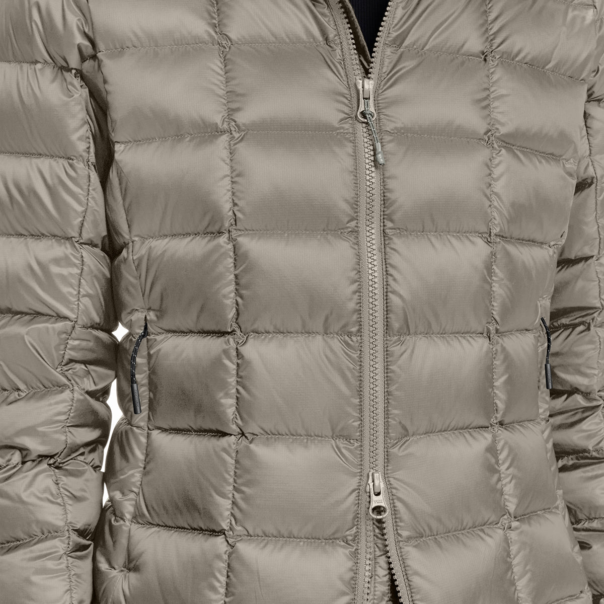 Close-up of a quilted puffer jacket in a warm grayish-beige or taupe color, featuring a central silver zipper and horizontal baffles.