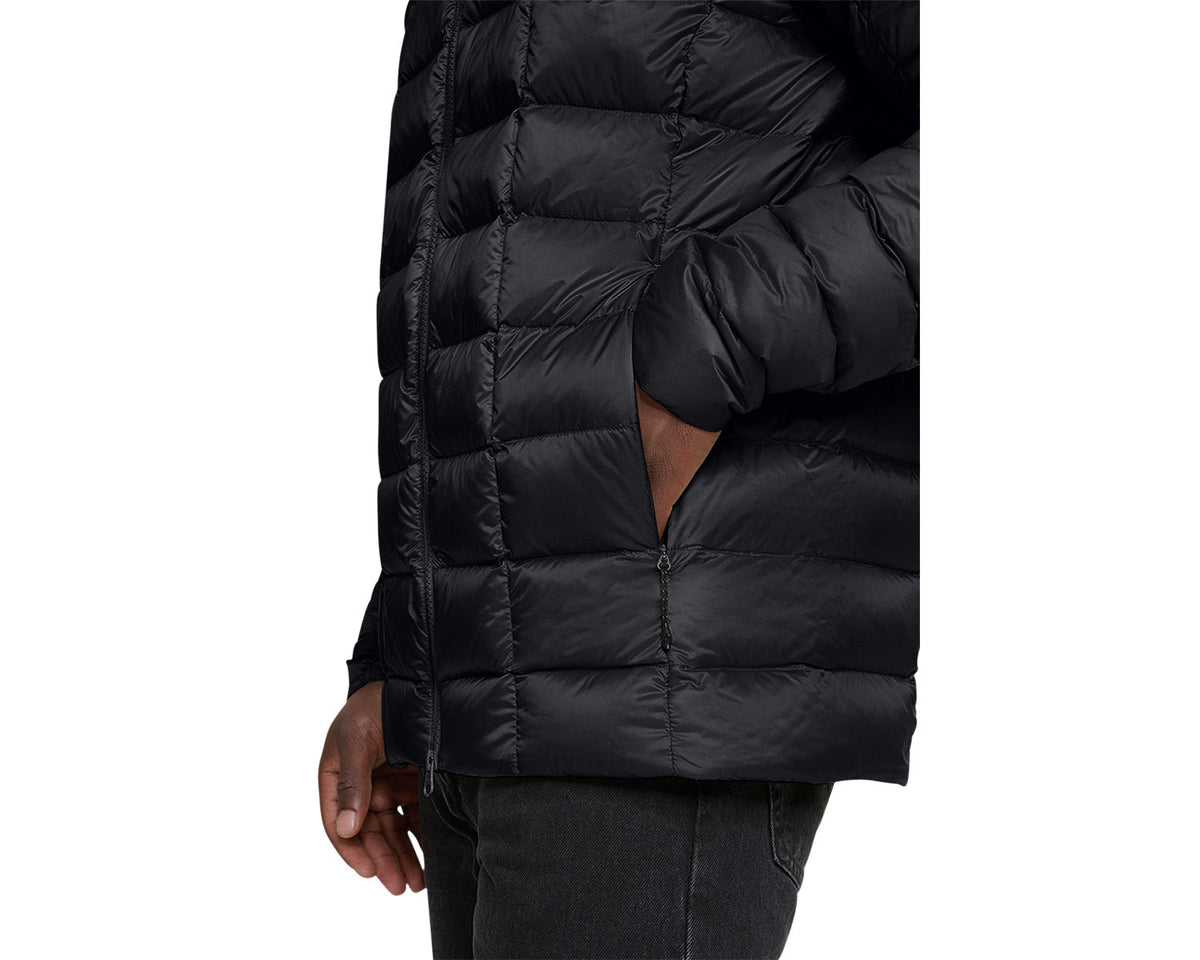 Black puffer jacket worn by a person on a white background