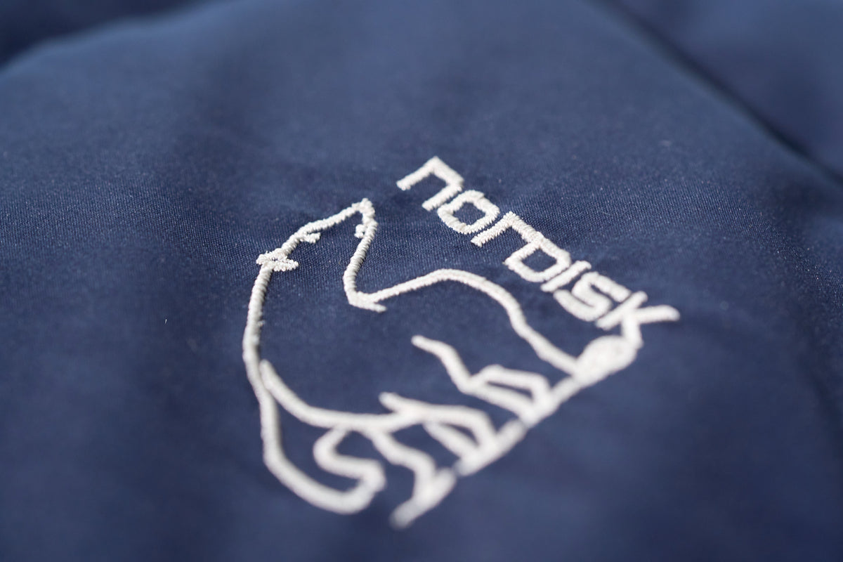 Nordisk logo embroidered on a dark blue fabric surface
