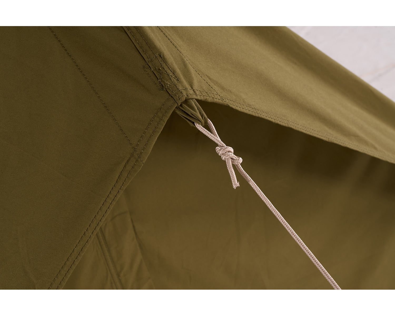 Close-up of a green tent with a rope tie, showing detailed stitching.