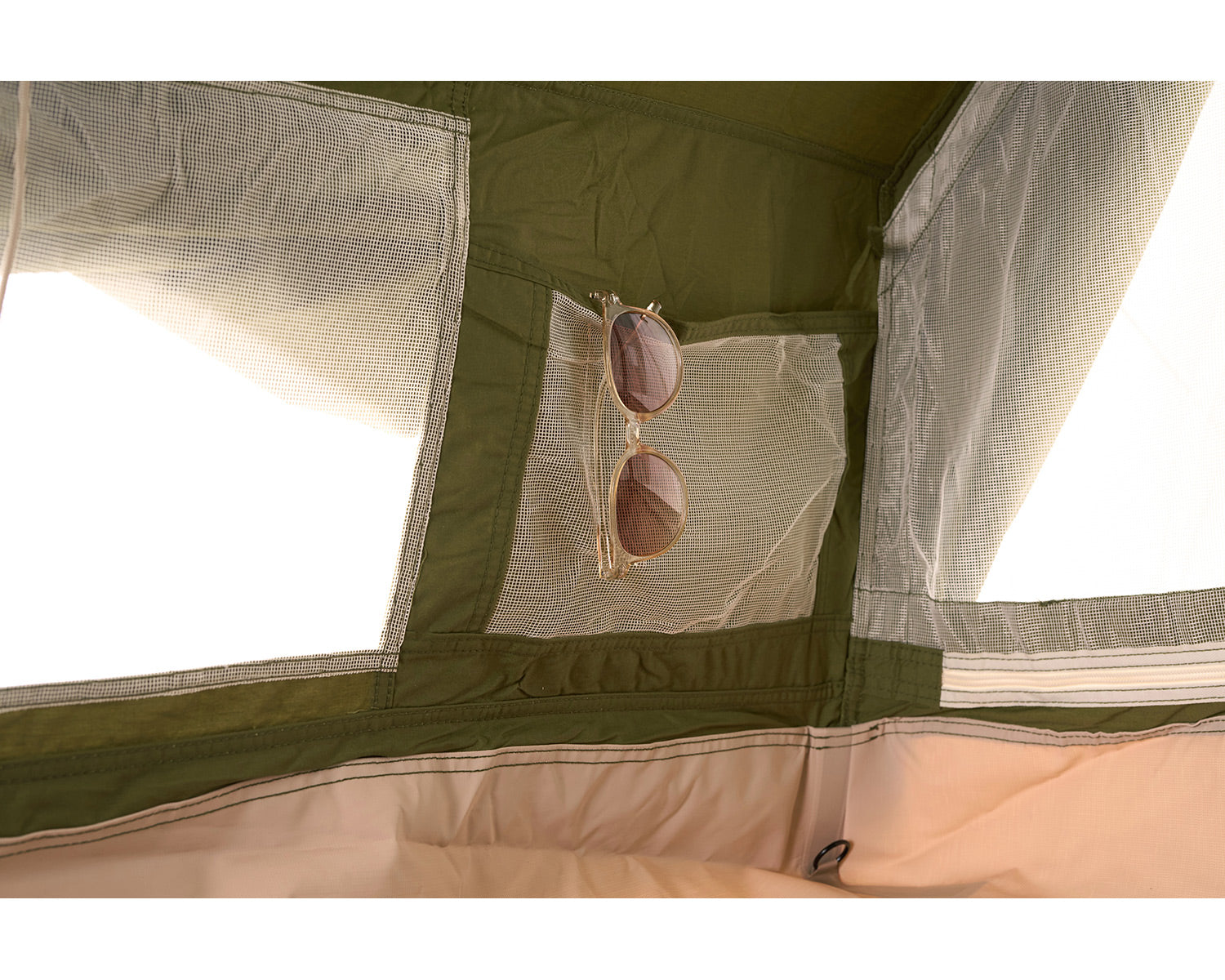 Sunglasses hanging inside a green and beige tent with mesh sides.