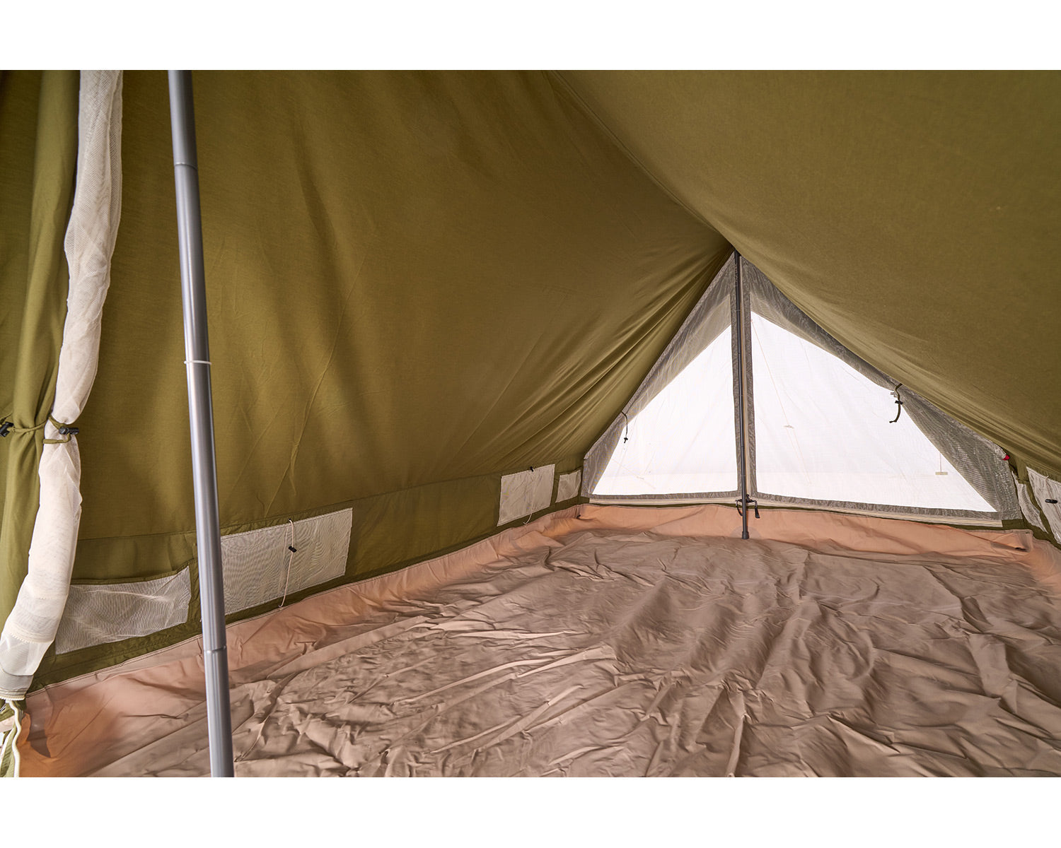 Interior of a green camping tent with a mesh window and bedding.
