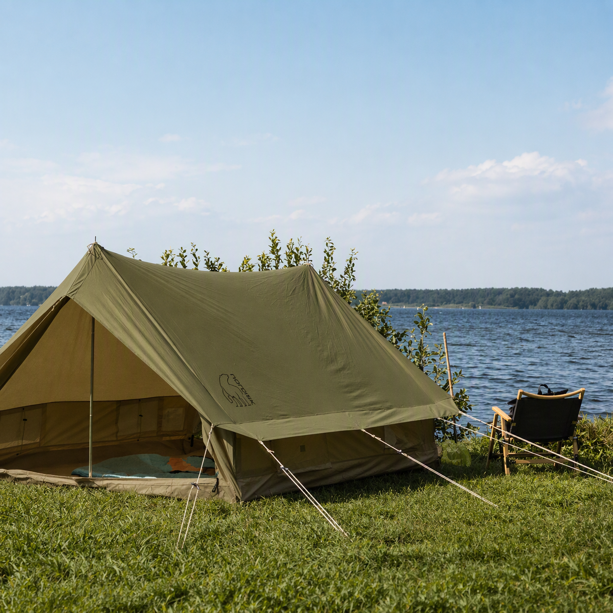 Green tent set up near a body of water with a clear sky