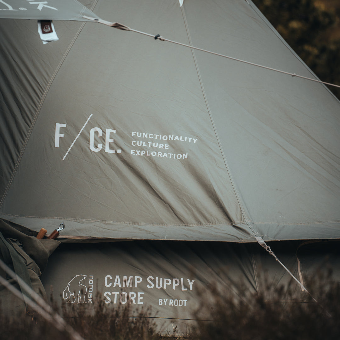 Tent with 'F/CE.' branding and 'Camp Supply Store by Root' text in a natural setting.
