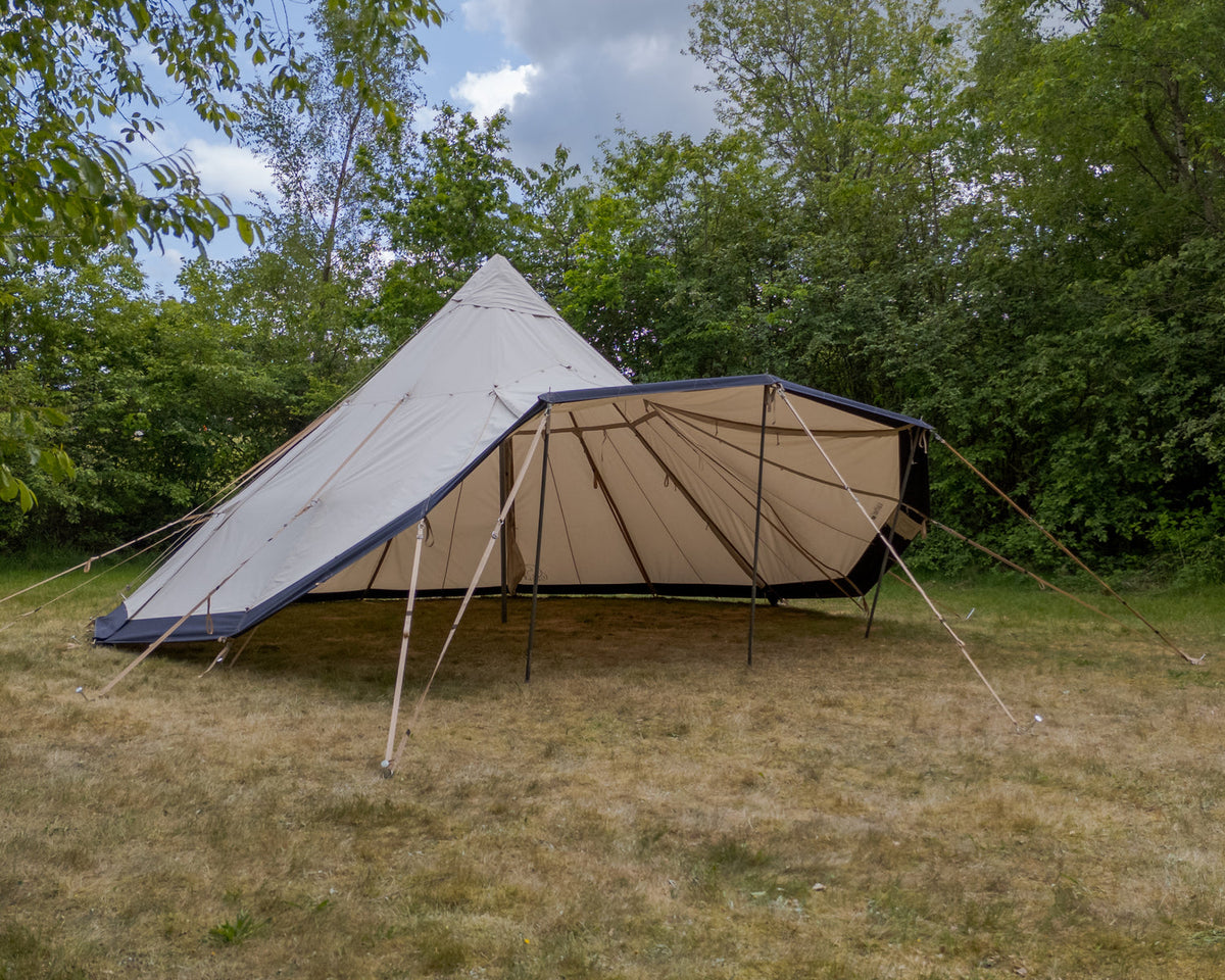 Teepee-style tent with a white roof and beige walls in a forest setting