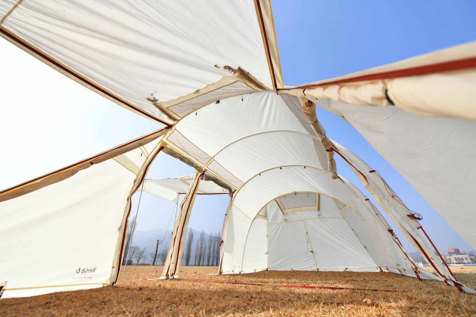 Large white tent structure with a clear blue sky background
