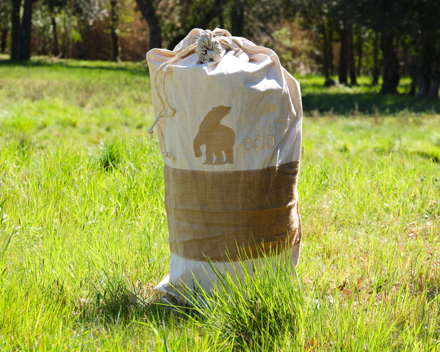 Canvas drawstring bag with eco logo on grassy field