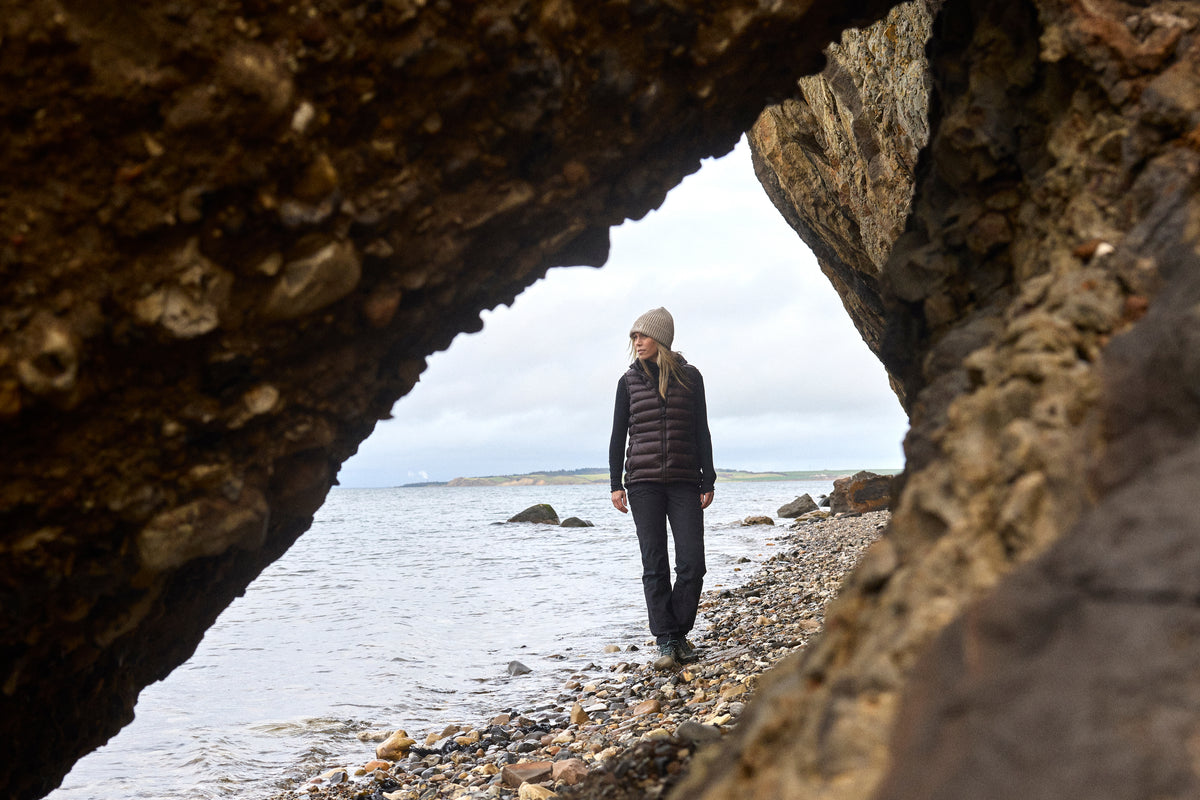 Frau in Nordisk Companyon in einer Felshöhle an der Küste