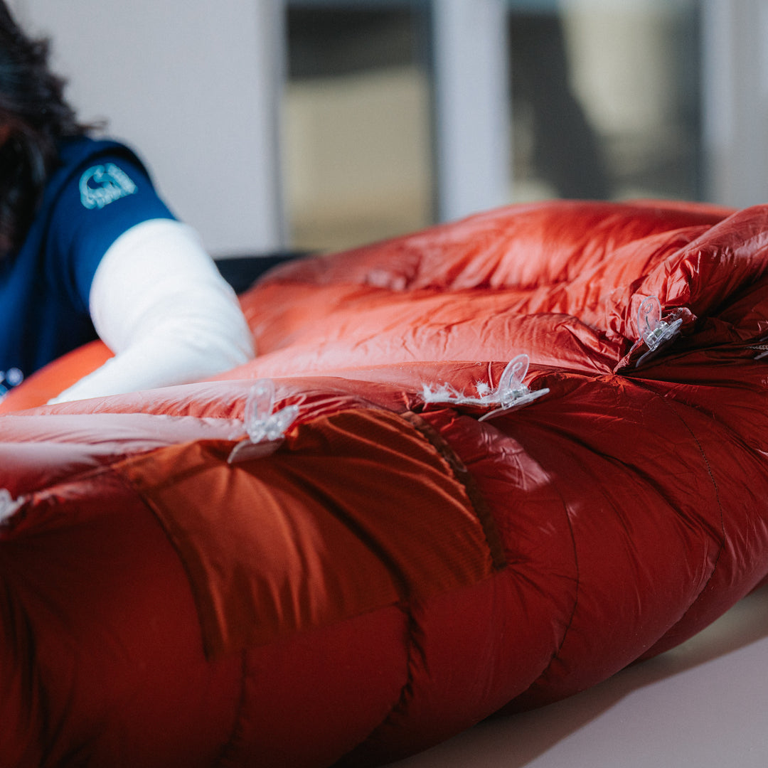 Näherin arbeitet an einem roten Daunenschlafsack in der Manufaktur in Görlitz