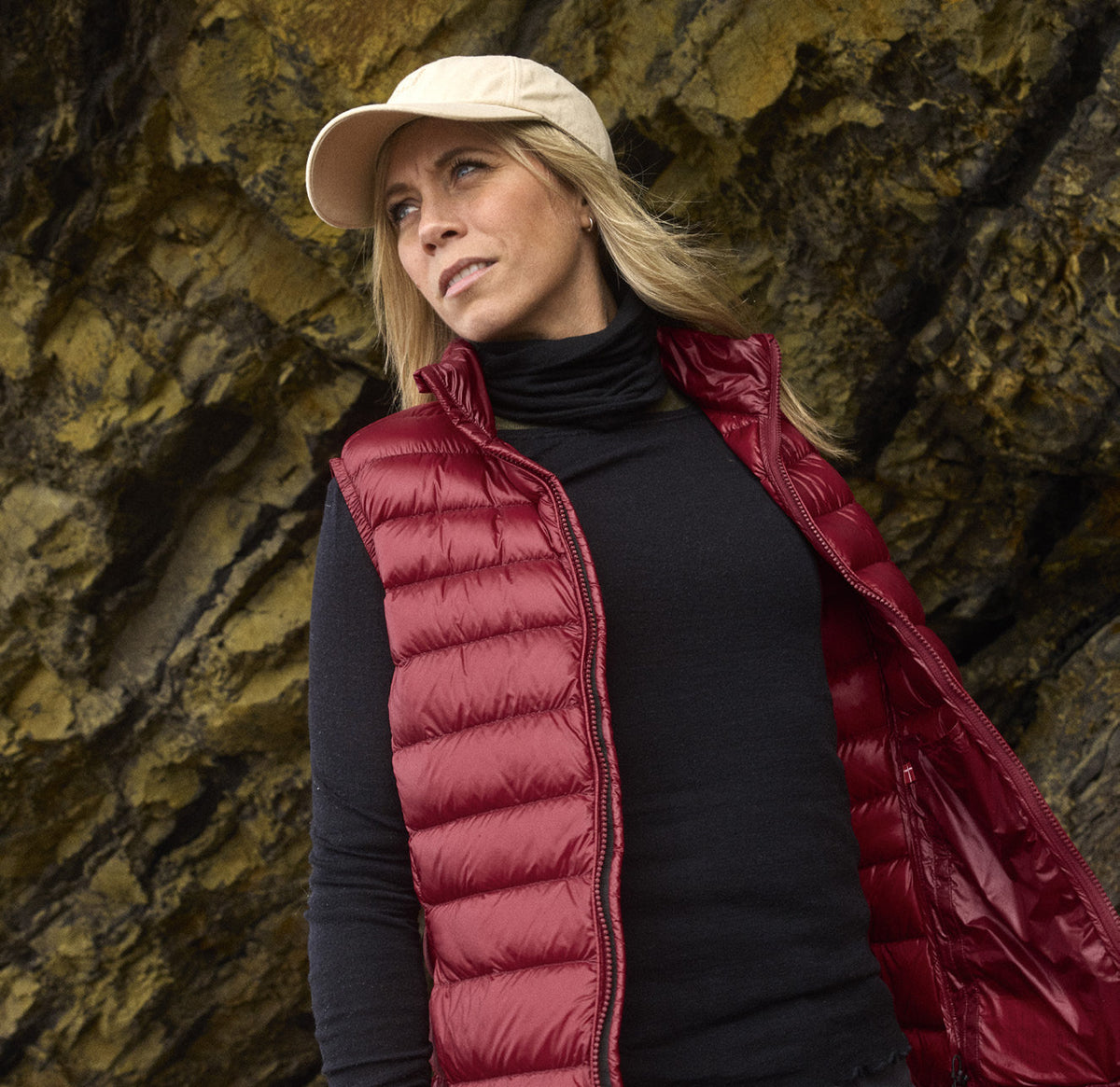 Frau in der Companyon Daunenweste Asta in Tibetan Red vor einer Felswand
