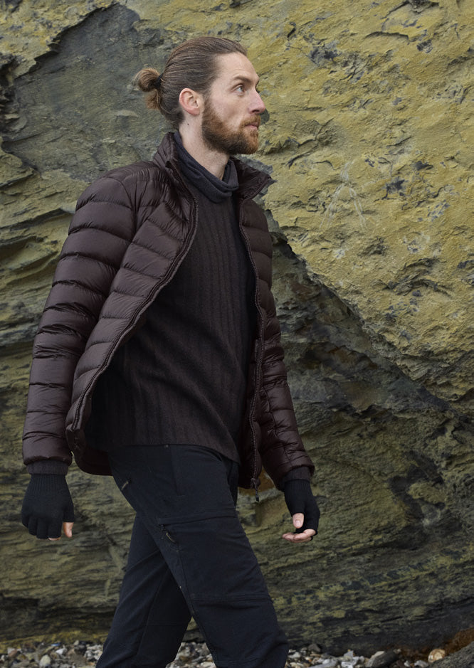 Mann in der Companyon Daunenjacke Hjalte in Black Coffee an einer Felswand